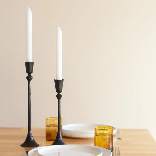 Vintage style metal candlesticks in black with white candles on a dining table setting