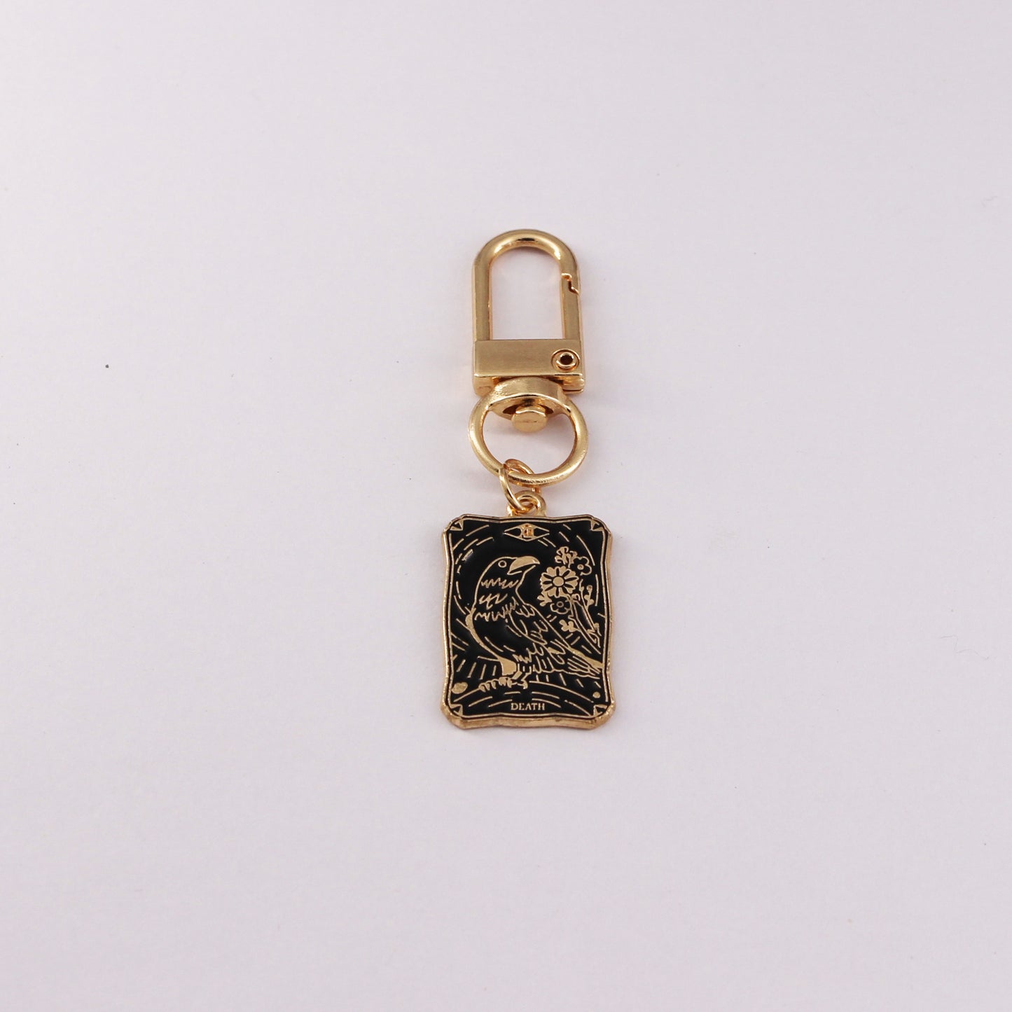 Gold keychain with a black rectangular pendant on a white background