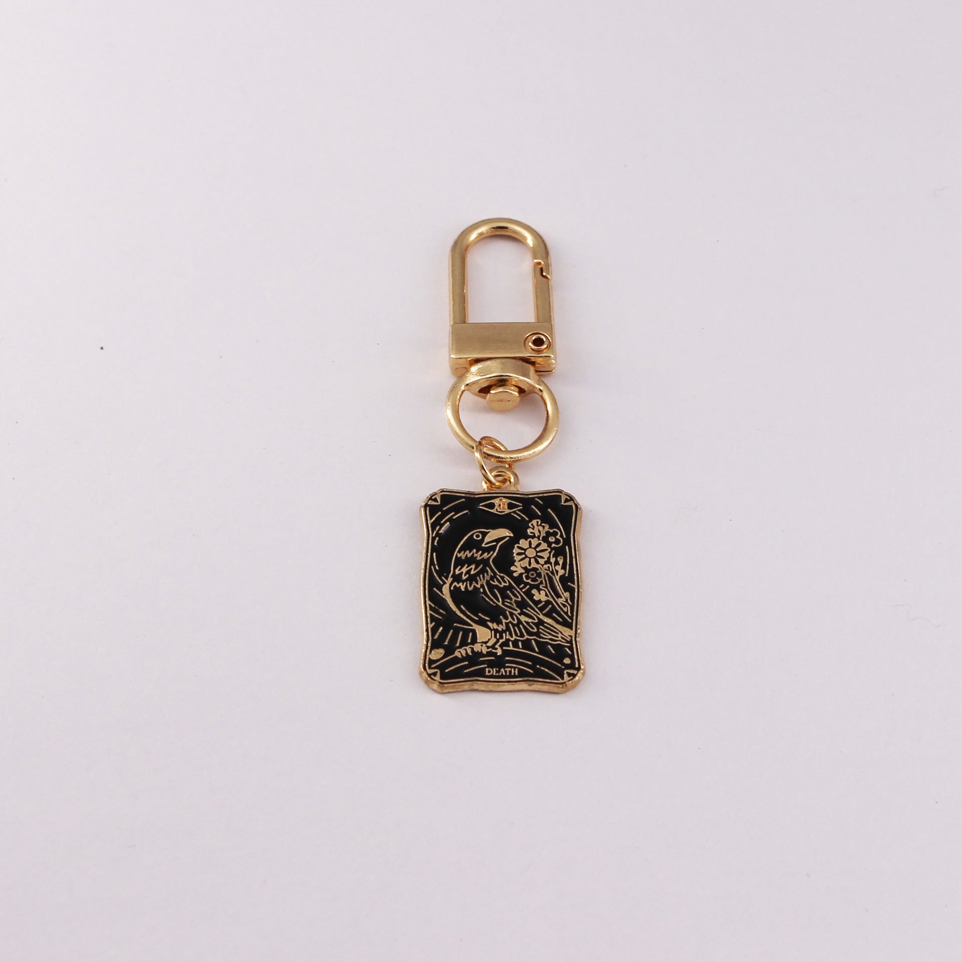 Gold keychain with a black rectangular pendant on a white background