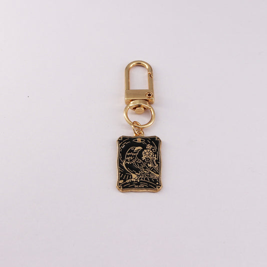 Gold keychain with a black rectangular pendant on a white background