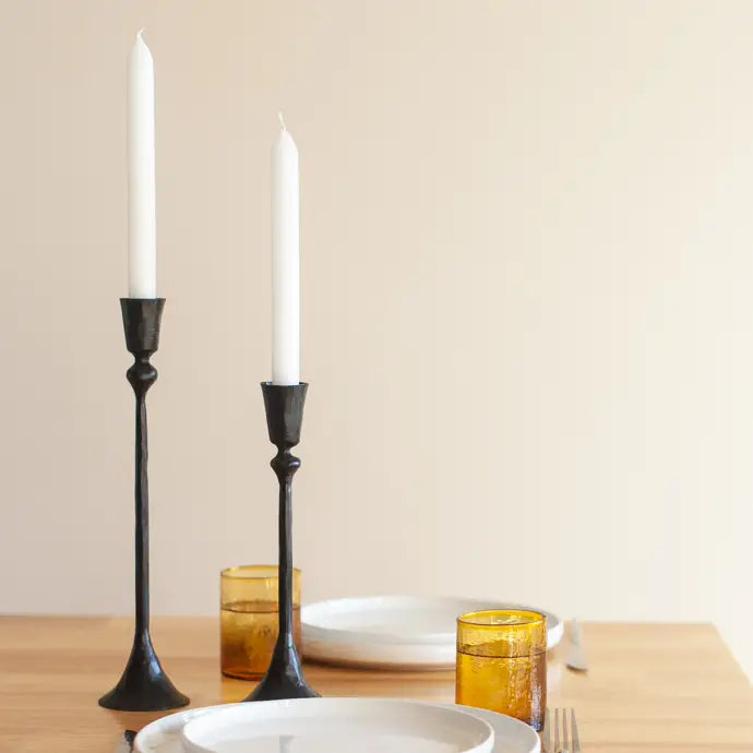 Vintage style metal candlesticks in black with white candles on a dining table setting